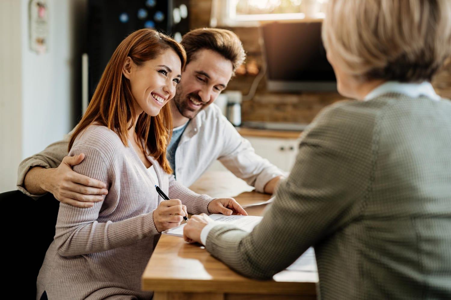 young-happy-woman-her-husband-signing-agreement-with-insurance-agent-during-meeting